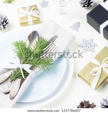 Christmas table setting with plates, silverware, presents, candles and decorations