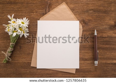 Envelope, pen and flowers daisy on a wooden background   	