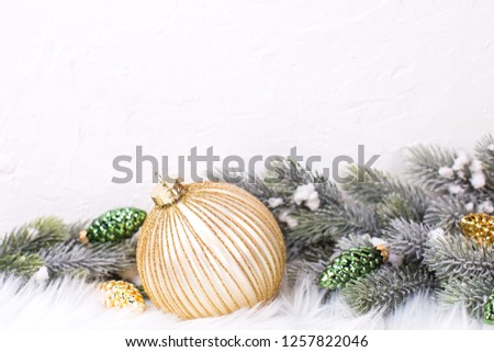 Border from gold ball and golden  and green pine cones and branches fir tree near by white textured wall. Decorative christmas composition. Selective focus. Place for text.

