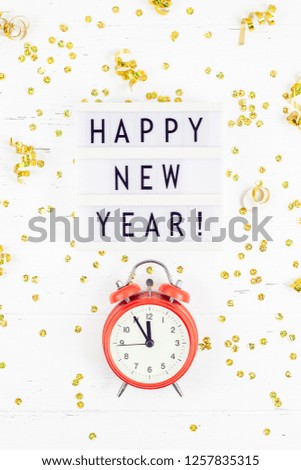 New Year or Christmas pattern flat lay top view red alarm clock twelve midnight Xmas holiday celebration white wooden golden sparkles confetti background. Template for your text design 2019