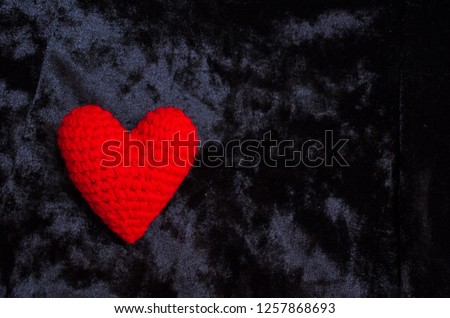 red heart knitted from yarn lies on a black beautiful background