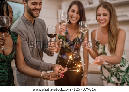 Party with friends. Group of cheerful young people carrying sparklers and champagne flutes - Image