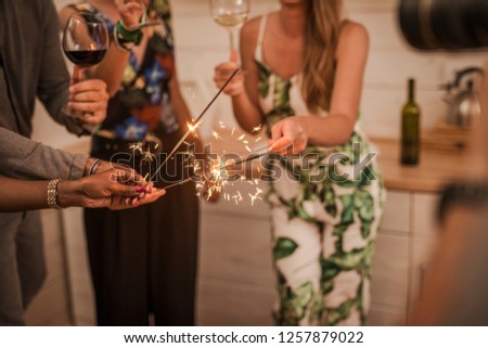 Party with friends. Group of cheerful young people carrying sparklers and champagne flutes - Image