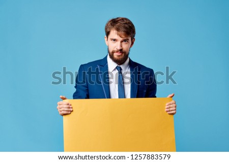 A business man in a suit holds in his hand a yellow sheet of paper                       