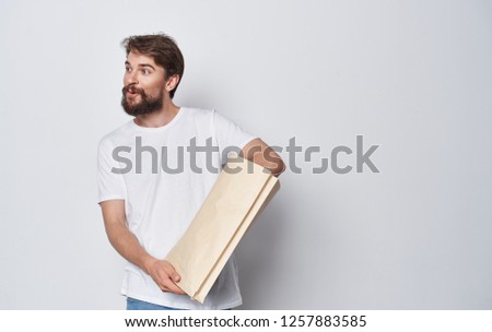 Bearded man with a package on light background                   