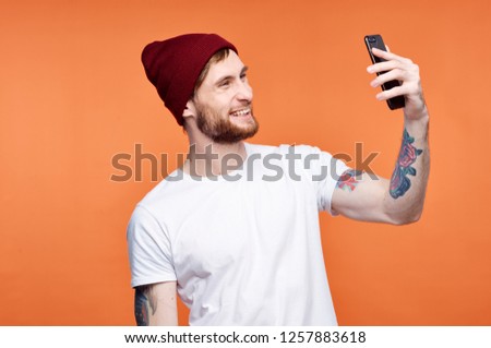 A happy man in a red cap with a tattoo holds a phone in his hand                  