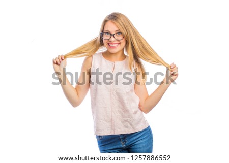 Playful young blonde holds her hair with both hands with her hands apart, woman's emotions, filming on an isolated background