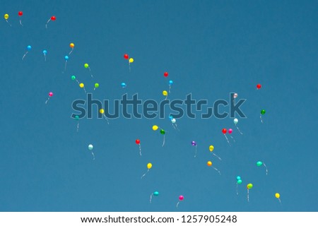 colored and multi-colored gel balloons are flying in a group of bright blue skies