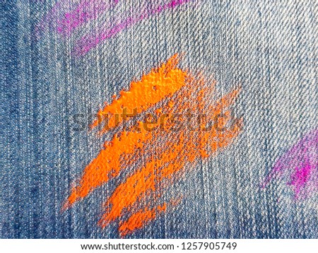 The texture of denim with strokes of fluorescent gouache color paint. Abstract background jeans