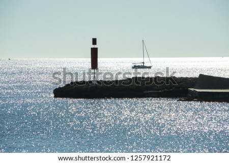 Sailboat and pier with inlet on a bright sunny day in December in Mallorca, Spain.