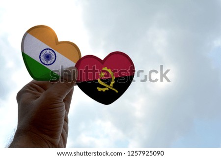 Hand holds a heart Shape India and Angola flag, love between two countries