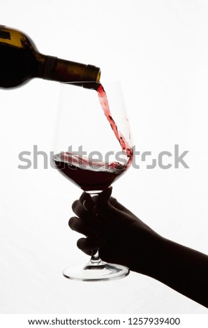 red wine is poured into a glass on a white background