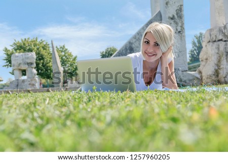 Young smiling woman laying down on the grass and looking at camera