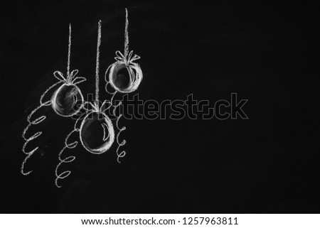 Christmas balls hanging on the branches of a Christmas tree painted with chalk on the Board