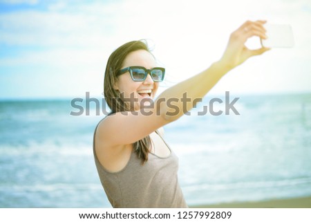 Smiling woman is taking selfie at the seaside. toned photo