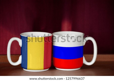 Russia and Romania flag on two cups with blurry background