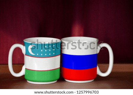 Russia and Uzbekistan flag on two cups with blurry background