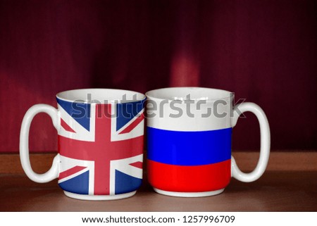 Russia and United Kingdom flag on two cups with blurry background