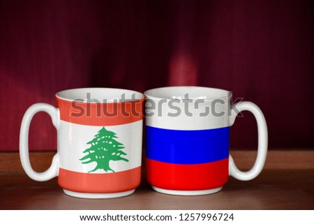 Russia and Lebanon flag on two cups with blurry background