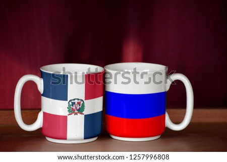 Russia and Dominican Republic flag on two cups with blurry background