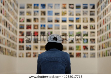The back of a woman wearing a white hat. See a lot of pictures in the museum.