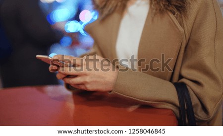 Close up of female hand using phone. Young woman using mobile phone in a city at night.