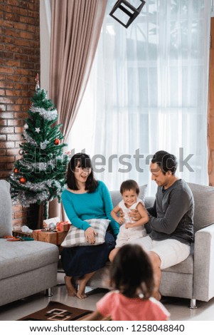 portrait of happiness family sitting on a couch beside christmas tree and a daughter come in living room