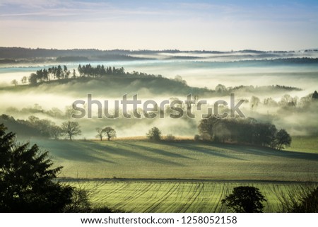 Stunning winter morning scene at Newland's Corner in the North Downs with fog in the valley. Countryside landscape in the Surrey Hills Area of Natural Beauty, UK. Royalty-Free Stock Photo #1258052158