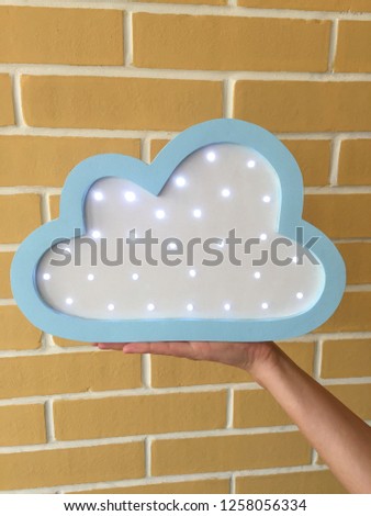 Beautiful soft blue night light in the shape of a cloud on the background of decorative bricks