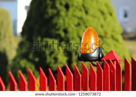 Orange room alarm light located on a brick fence post. Intercom apartment building at the entrance to a private protected area. Hazard alert. Intercom for door curtain. Property Protection and Securit
