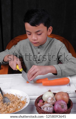 Asian kid cutting carrot on chop board