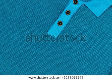 Jersey-Poloshirt with brown wooden buttons. Jersey Polo shirt clasp with brown wooden buttons. Blue polo shirt, close up fashion background.  