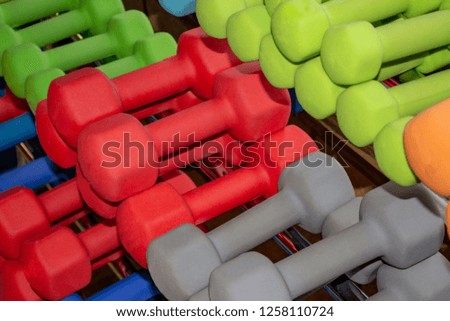 Dumbbells of different colors and sizes in the gym for sports