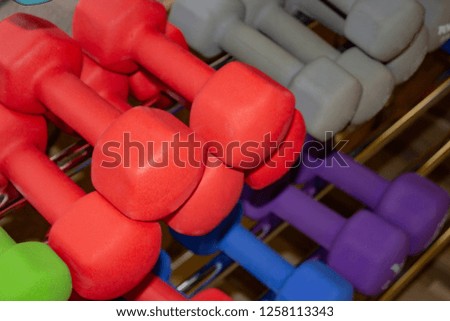 Dumbbells of different colors and sizes in the gym for sports