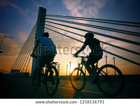 Couple riding bicycle crossing the bridge when sunrise 