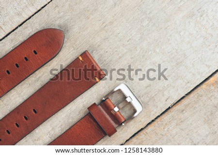 Brown leather handmade watch strap with steel buckle on rustic wooden surface. Closeup. Copy space. 