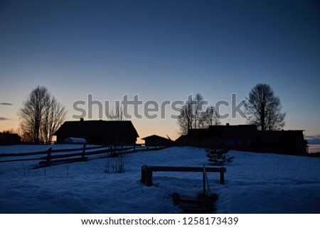 Winter evening landscape in the village, the silhouettes of houses against a dark blue sky
