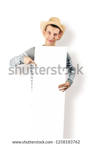 A young guy in a cowboy hat is holding a blank billboard - isolated on white