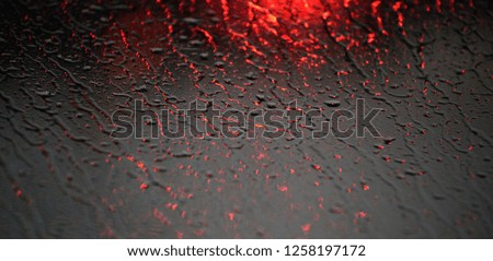 abstraction of the rain in the rearview mirror of a car where the drops and the lights of the headlights are confused.