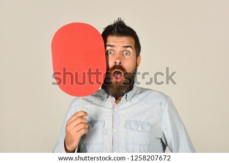 Surprised bearded man hold paper nameplate. Feeling&emotions. Facial expression. Fashion, beauty, hairdressing, barber salon. Amazed man with beard&mustache. Red blank paper. Man with empty name card.