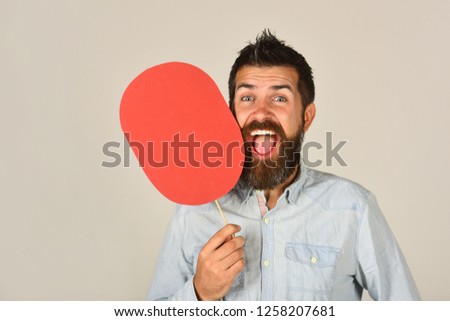 Laughing bearded man hold paper name plate. Feeling&emotions. Face expression. Fashion, beauty, hairdressing, barber salon. Cheerful man with beard&mustache. Red blank paper. Man with empty name card.