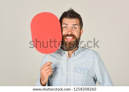 Smiling bearded man hold paper nameplate. Feeling&emotions. Facial expression. Fashion, beauty, hairdressing, barber salon. Laughing man with beard&mustache. Red blank paper. Man with empty name card.