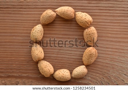 a horizontal of the letter O shaped with almonds on wood Royalty-Free Stock Photo #1258234501