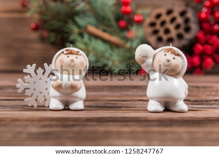 Two figures of children playing snowballs on a dark wooden textured background. Christmas toys and snowflakes