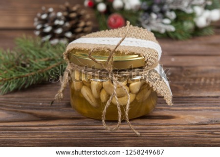 Honey jars with nuts in gift packaging kraft. Wreath. Christmas winter frame on dark wooden background. Red elements. New Year's gifts.