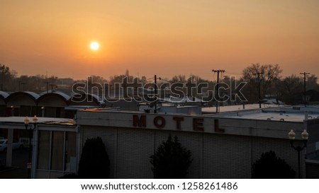 Beautiful red and orange sunset on a smoggy winter evening in Provo Utah. View of an old motel and city.
