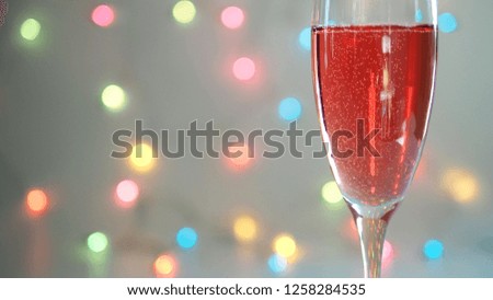 Christmas and New Year celebrations theme Sparkling Red Wine or Champagne in a glass with pastel rainbow bokeh defocused lights background. Holidays party concept. (selective focus, space for text)