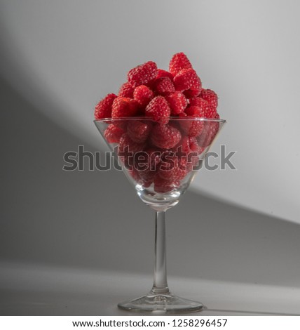 Fresh raspberries in a glass beaker isolated on white background.