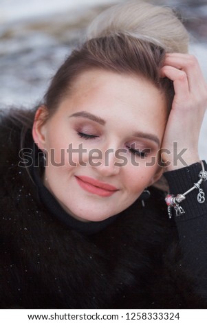 Closeup portrait girl sitting on a snow in the city on curb covered with snow. Lifestyle. winter mood, coffee cup, mink fur clothing.