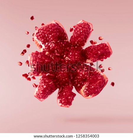 Flying in air fresh ripe pomegranate isolated on pink background. High resolution image